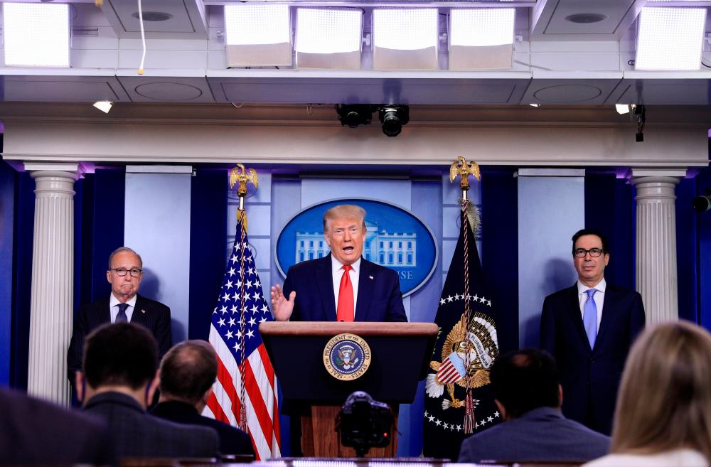 Trump is flanked by his economic adviser Larry Kudlow (left) and US Treasury Secretary Steven Mnuchin as he speaks during a press briefing on the US economy and new US employment and unemployment numbers in the White House in Washington today. – REUTERSPIX