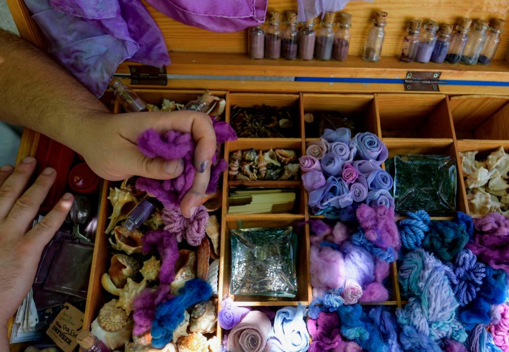 Tunisian craftsman Mohamed Ghassen Nouira displays a box where he keeps samples of yarn and fabric dyed with a purple color he extracted from Murex shells at his workshop in the capital Tunis, on July 11, 2020. / AFP / FETHI BELAID