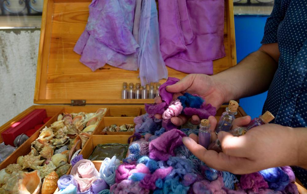 Tunisian craftsman Mohamed Ghassen Nouira displays a box of yarn and fabric dyed with a purple color he extracted from Murex shells at his workshop in the capital Tunis, on July 11, 2020. / AFP / FETHI BELAID $!Tunisian craftsman Mohamed Ghassen Nouira displays a box of yarn and fabric dyed with a purple color he extracted from Murex shells at his workshop in the capital Tunis, on July 11, 2020. / AFP / FETHI BELAID