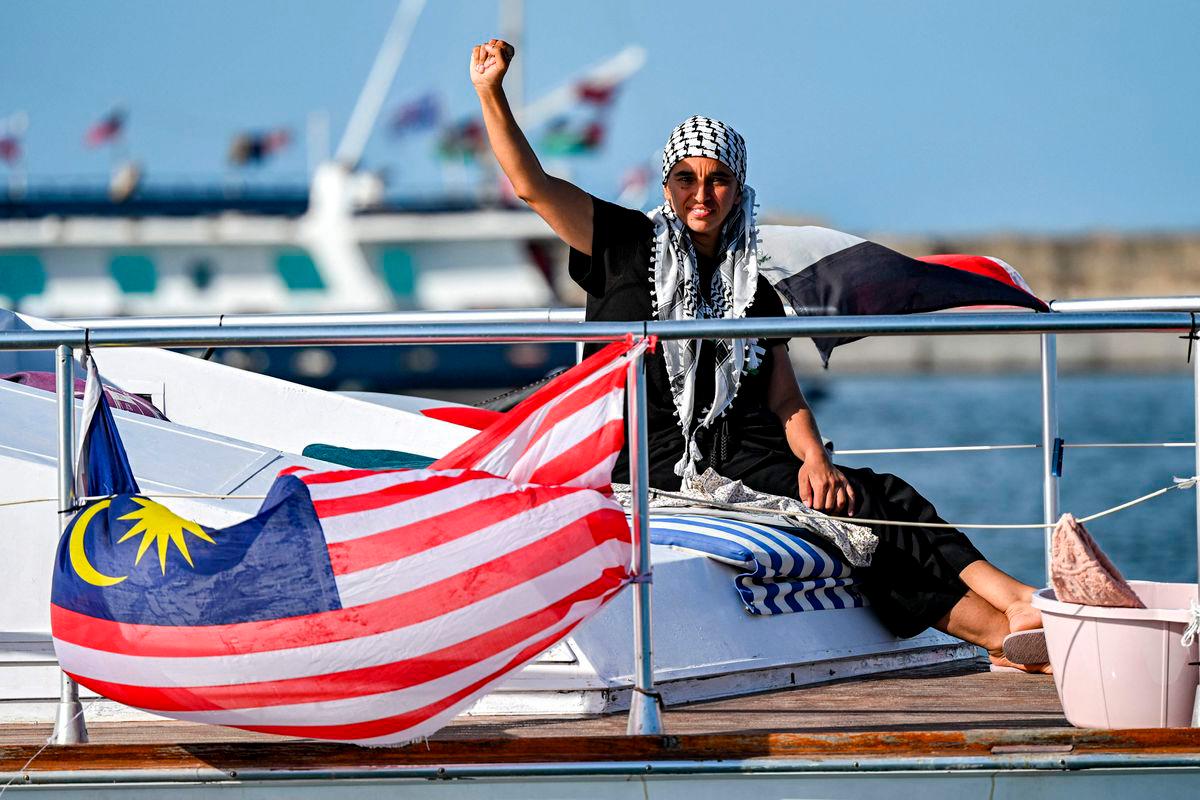 A woman gestures as she rides aboard a vessel with other activists and human rights defenders, departing from Tunisia’s northern port of Bizerte, on September 14, 2025. (Photo by MOHAMED FLISS / AFP)