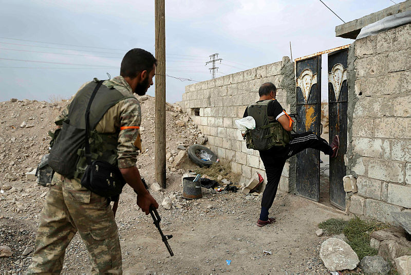 Turkey-backed Syrian fighters breakopen the front door of a house at a postition that they are holding in the Syrian border town of Ras al-Ain on Oct 19, 2019. — AFP