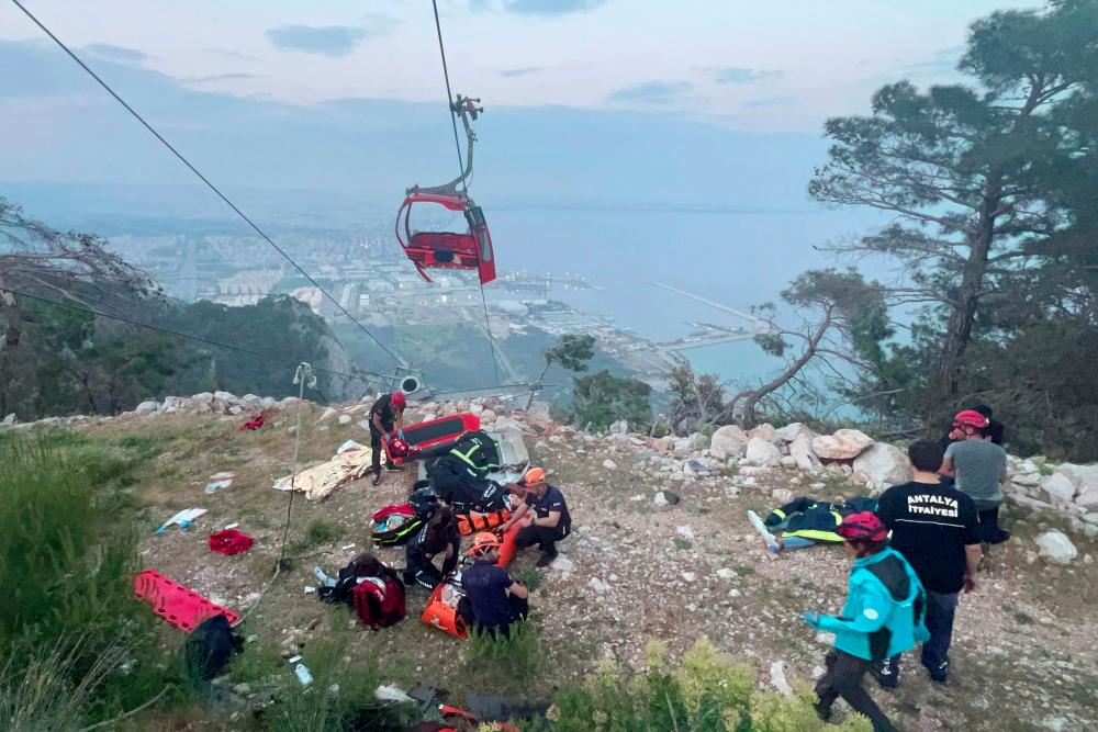 This handout photograph taken and released on April 12, 2024 by Turkish news agency DHA (Demiroren News Agency) shows rescue teams conducting a rescue operation and helping injured people after a cable car cabin crashed into a fallen cable pole in Konyaalti district of Antalya. - AFPPIX