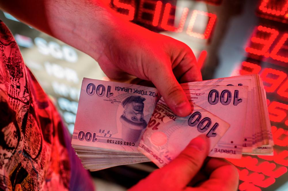 A money changer counts Turkish lira banknotes currency exchange office in Istanbul. The lira on Thursday broke through 18 to the dollar for the first time since December and set a record closing low of 18.089. – AFPpix