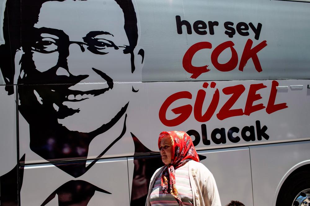 A woman walks next to bus of Ekrem Imamoglu (unseen), Istanbul mayoral candidate of the main opposition Republican People’s Party (CHP), during a election campain at Zeytinburnu district in Istanbul on May 29, 2019. — AFP