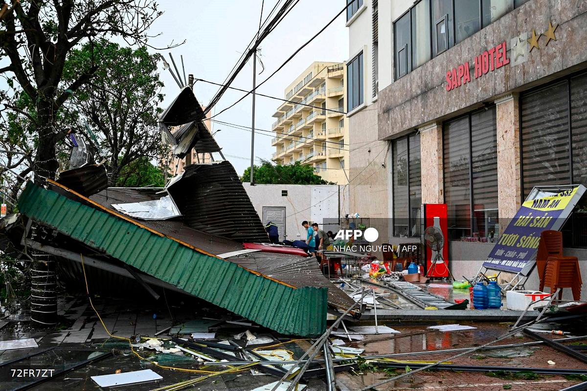 Workers clear the debris of a collapsed corrugated iron roof near Cua Lo beach after Typhoon Kajiki passed through Nghe An province on August 26, 2025. - Nhac NGUYEN / AFP
