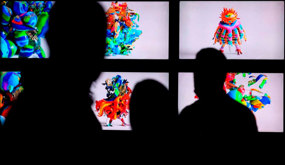Visitors stand in front of works by Uta Bekaia x Denis Davydov, entitled Sacred Creature Bajbaja - Svadhisthanas Family, 2021, CGI, NFT, courtesy of Window Project and Instigators, displayed during the 15th edition of Art Dubai at Madinat Jumeirah in the Gulf emirate of Dubai, on March 10, 2022. AFPPIX