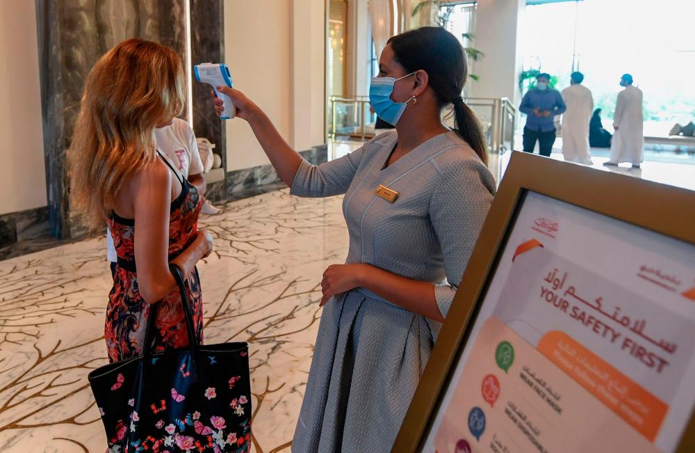 $!A member of staff checks the temperature of a tourist at the Al Naseem hotel in the Gulf emirate of Dubai in the United Arab Emirates, on July 7, 2020. With a “welcome” passport sticker and coronavirus tests on arrival, Dubai reopens its doors to international visitors in the hope of reviving its tourism industry after a nearly four-month closure. / AFP / KARIM SAHIB