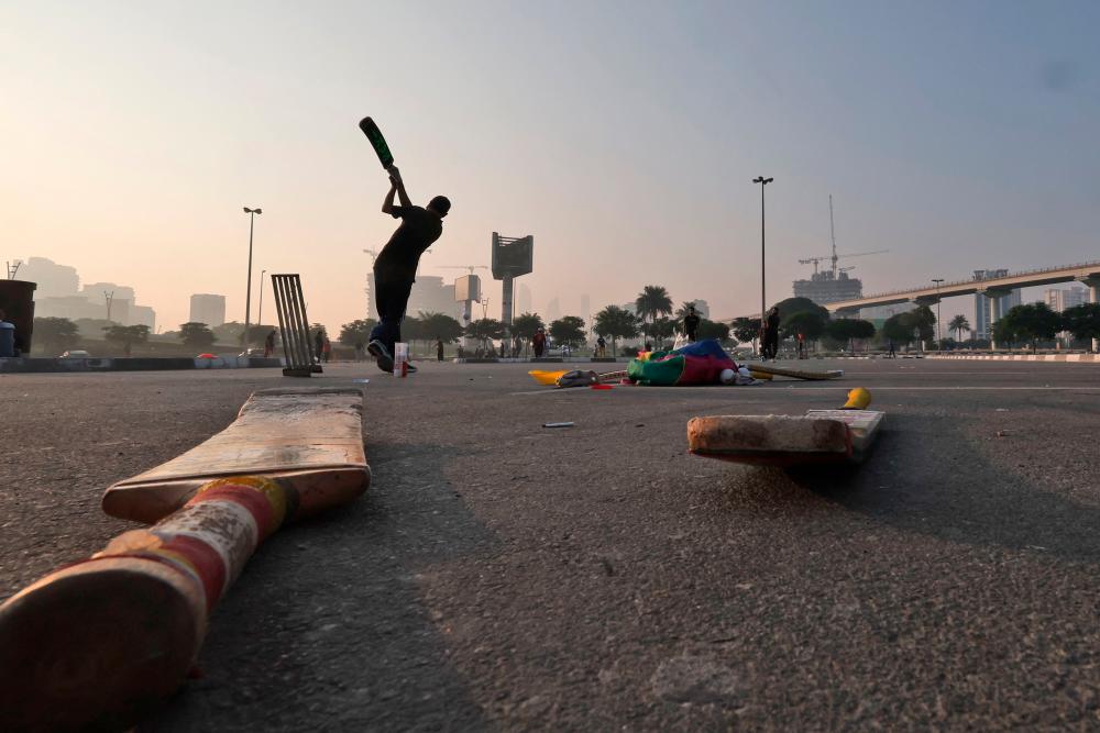 Expatriate workers play cricket in a parking lot in the Gulf emirate of Dubai on October 30, 2022. AFPPIX