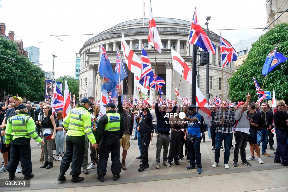Far-right Britain First party supporters wave Union Flags and St George Cross flags during an anti-immigration 'March for Remigration' calling for mass deportations, in Manchester, northwest England, on August 2, 2025. - PETER POWELL / AFP