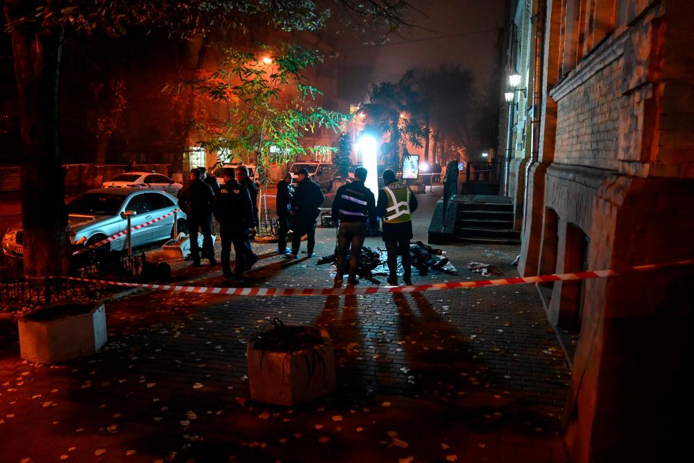 Police officers and investigators work at the scene where two men were killed in a suspected hand grenade explosion on Pushkinskaya street in downtown Kiev early on Oct 23, 2019. — AFP