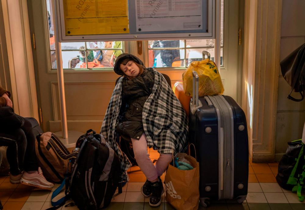 A girl sleeps next to suitcases as refugees from Ukraine wait in the main railway station in Przemysl, southeastern Poland, near the Polish-Ukrainian border on March 24, 2022, following Russia's invasion of Ukraine. AFPpix