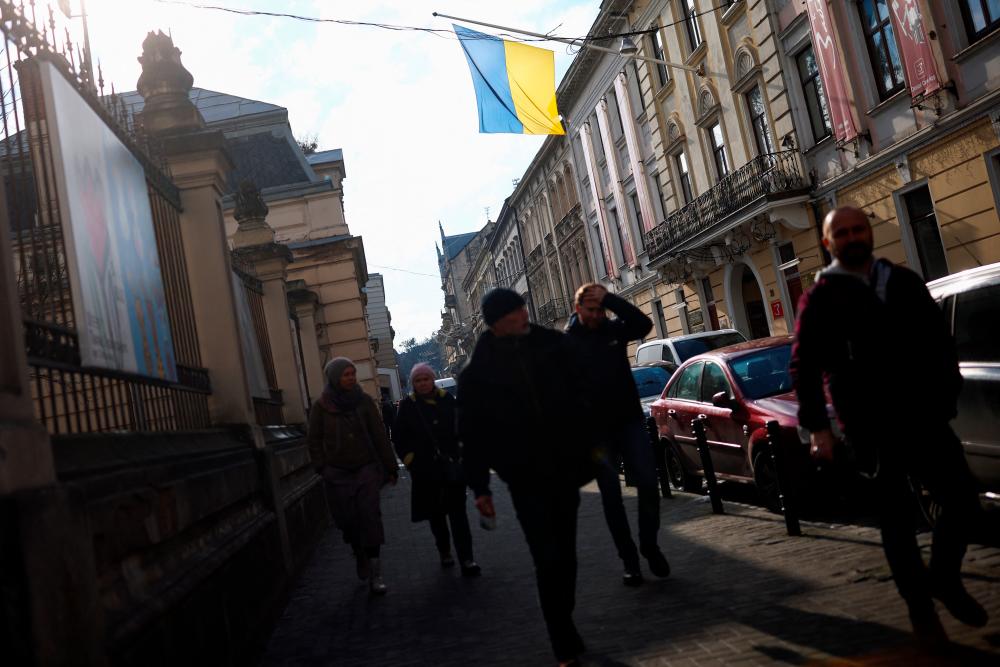 Ukrainian national flag flutters as people walk on a street in Lviv, Ukraine February 28, 2022. REUTERSpix