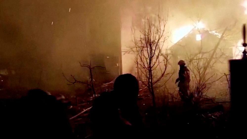 Firefighters walk on debris as a building burns following a Russian strike during Russia's invasion of Ukraine, in Zhytomyr, Ukraine, March 1, 2022 in this still image taken from video. State Emergency Service of Ukraine/via Reuters TV/Handout via REUTERSpix