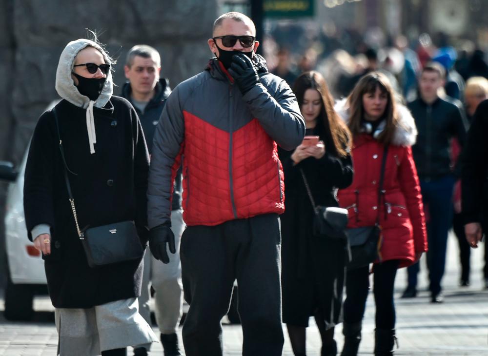 People wearing face masks as preventive measures against the COVID-19 outbreak, caused by the novel coronavirus, walk in the center of Kiev on March 16, 2020. – AFP
