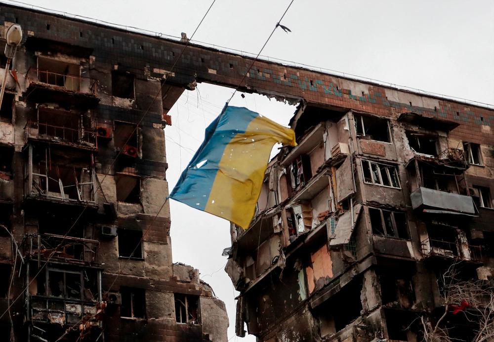 File photo: A view shows a torn flag of Ukraine hung on a wire in front an apartment building destroyed during Ukraine-Russia conflict in the southern port city of Mariupol, Ukraine April 14, 2022. REUTERSpix