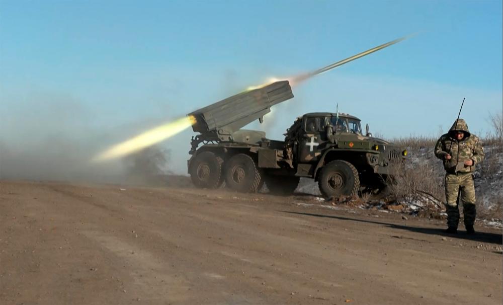 This grab taken from AFP video footage shows a member of Ukraine's military looking away as a BM-21'Grad' MLRS 122mm rocket launcher fires on the outskirts of Soledar on January 11, 2023. AFPPIX