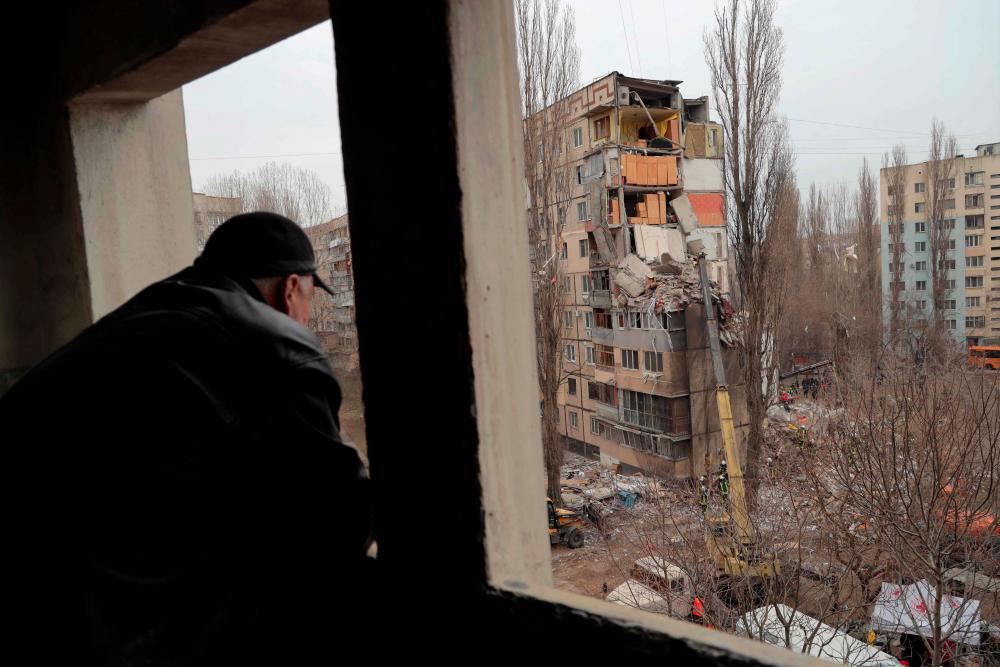 A local resident watches rescue works at the site of a heavily damaged multi-story apartment building, following a Russian drone attack, in Odesa, on March 2, 2024. - AFPPIX