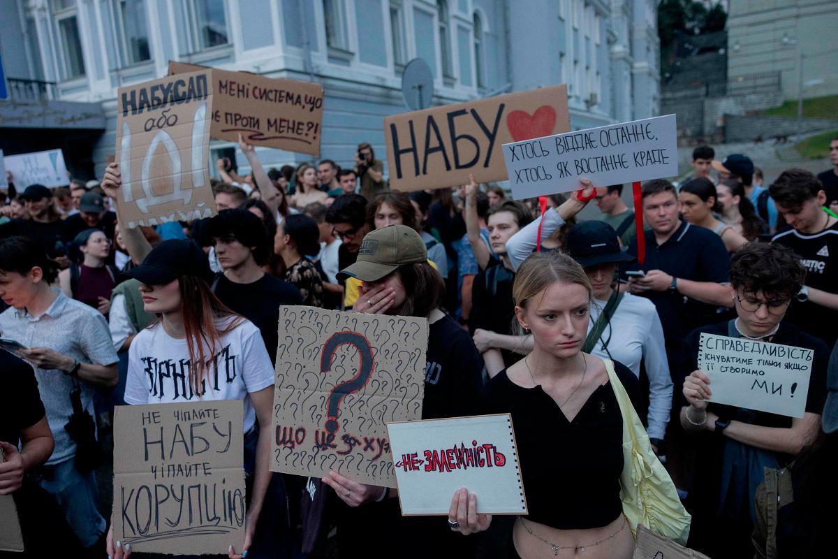 Protesters hold placards during a demonstration calling for the Ukrainian president to veto a law passed by parliament that reduces the powers of Ukraine’s National Anti-Corruption Bureau (NABU) and Specialised Anti-Corruption Prosecutor’s Office (SAPO) in downtown Kyiv on July 22, 2025, amid the Russian invasion of Ukraine. Ukraine’s parliament voted on July 22 to revoke the autonomy of the two anti-corruption agencies, a move that critics say will allow government meddling in high-profile graft cases. - Tetiana DZHAFAROVA / AFP