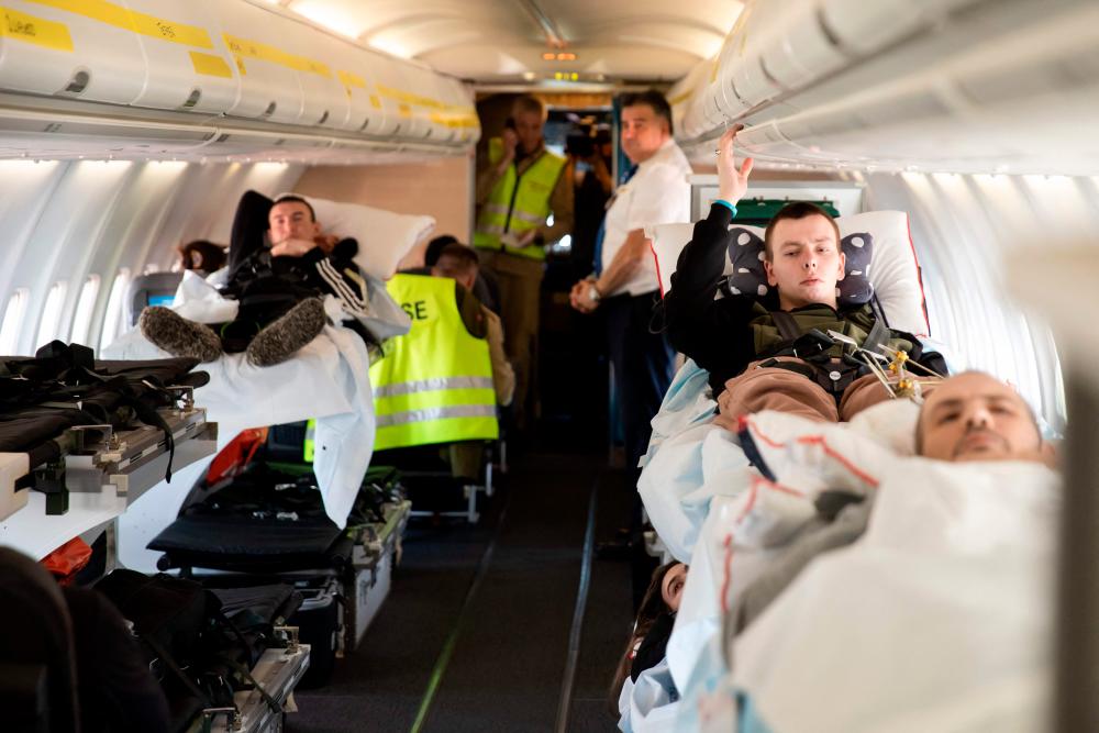 Wounded Ukrainian soldiers including Mykola Fedirko (R) are transported in a medical evacuation (Medevac) airplane, in Rzeszow, Poland on March 22, 2023/AFPPix