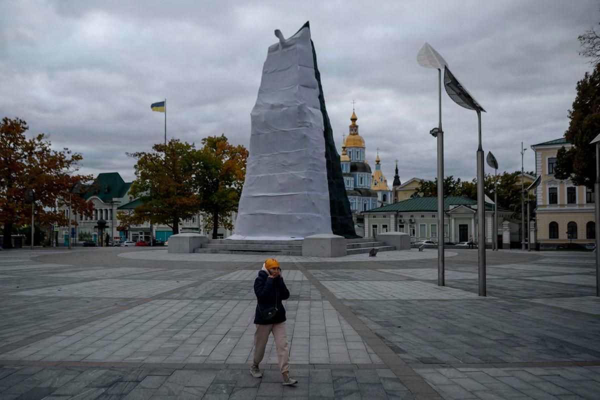 A pedestrian walks past the Independence Monument wrapped in a protective cover, in Kharkiv, eastern Ukraine on October 13, 2025. - AFPPIX