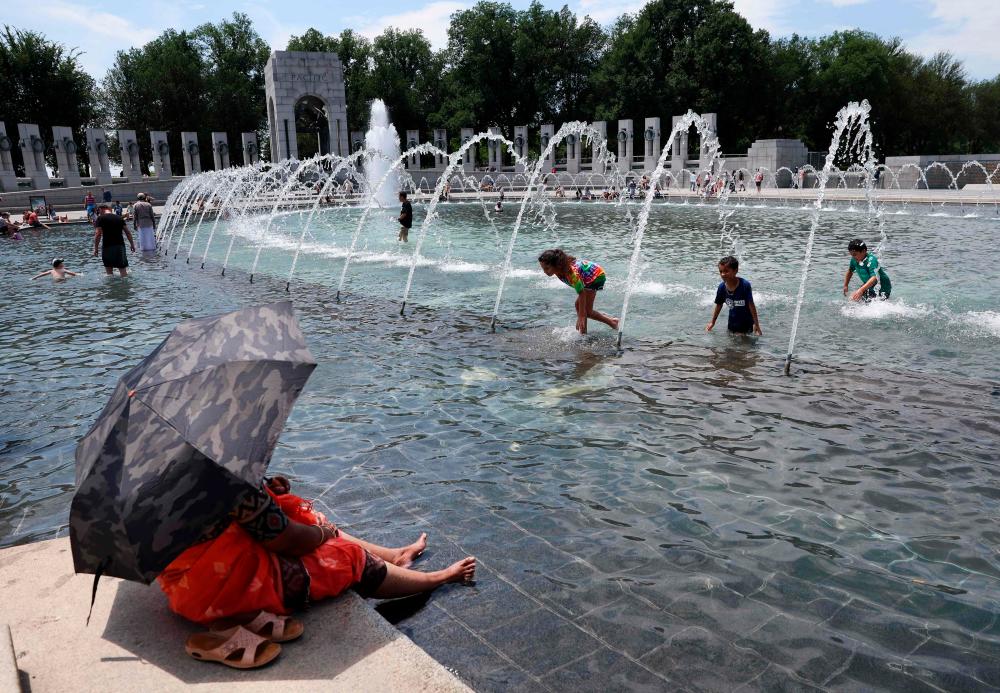 Visitors and tourists to the World War II Memorial seek relief from the hot weather in the memorial’s fountain on July 03, 2023 in Washington, DC/AFPPix