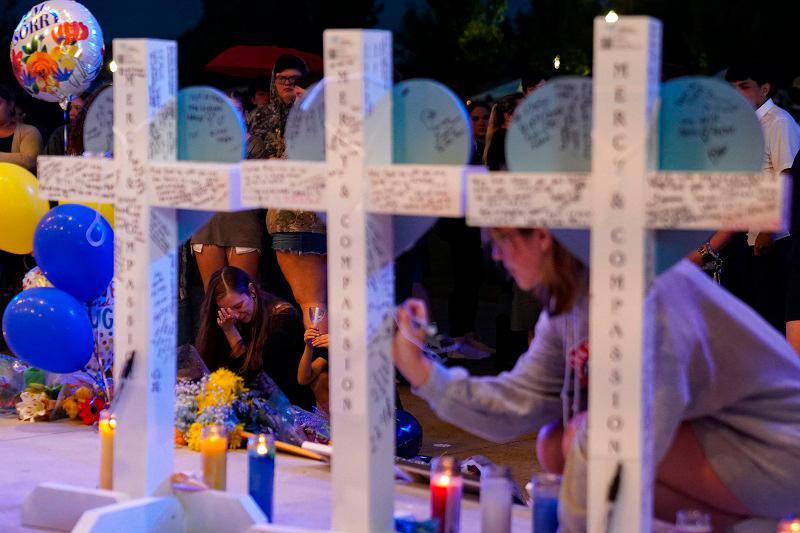 MONROE, GEORGIA - SEPTEMBER 06: A young girl writes on a cross after community members, students, and faculty of Apalachee High School came together for a vigil on September 6, 2024 in Monroe, Georgia. Two students and two teachers were shot and killed at Apalachee High School by a 14 year old student on September 4th, at least nine others were also injured in the incident. - Megan Varner/Getty Images/AFP