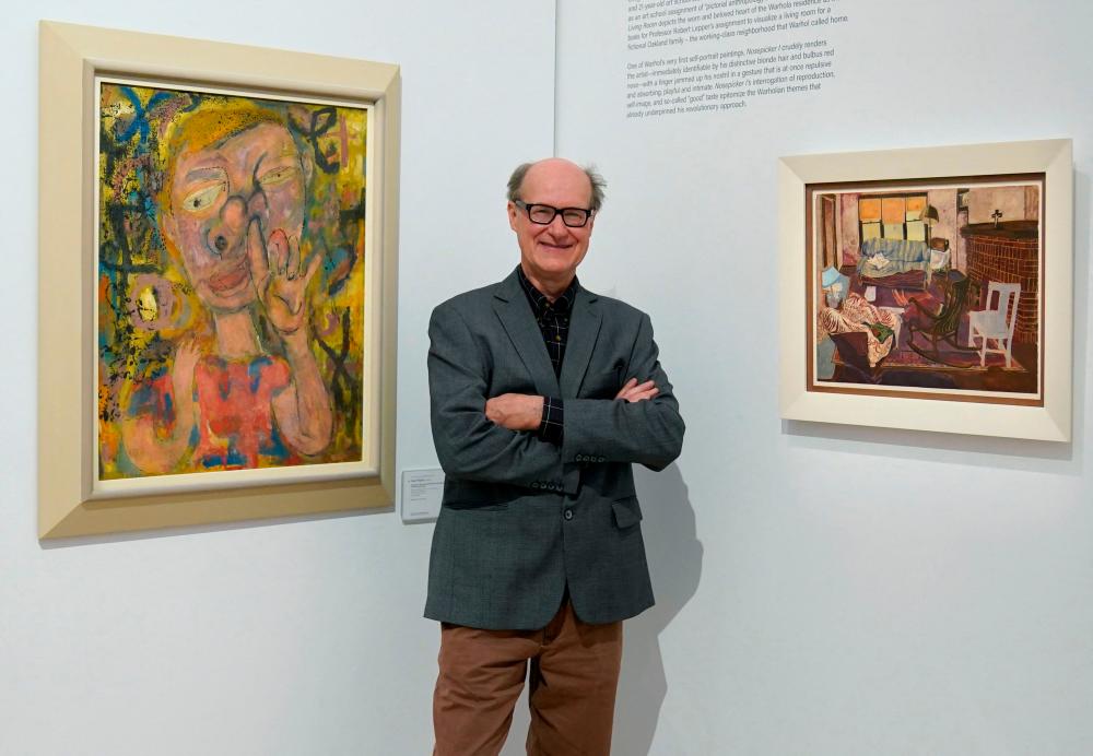 James Warhola, US artist and illustrator, stands next to his uncle Andy Warhol’s “Nosepicker 1: Why Pick on Me” and “Living Room” on display November 10, 2022 at Phillips Auction House in New York. AFPPIX