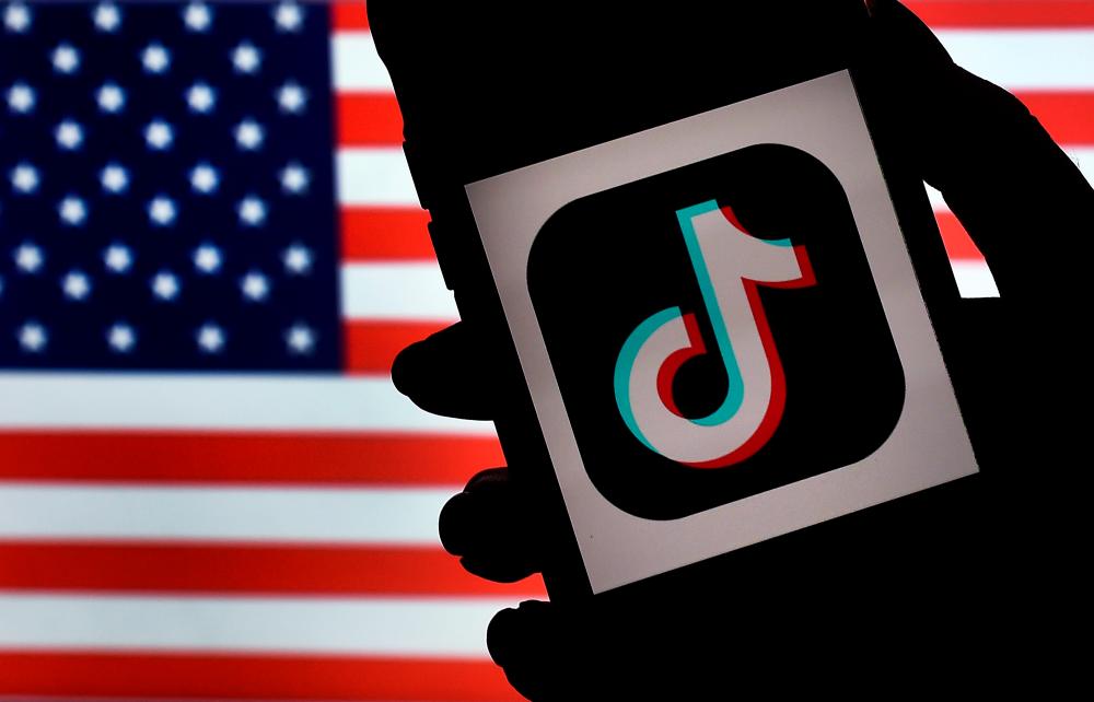In this photo illustration, the social media application logo, TikTok is displayed on the screen of an iPhone on an American flag background on Aug 3, 2020 in Arlington, Virginia. — AFP