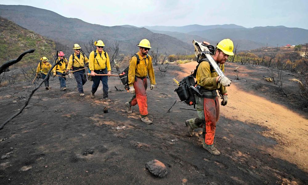 Firefighters walk on a scorched landscape from the Fairview Fire inside the San Bernardino National Forest near Hemet, California on September 9, 2022. AFPPIX