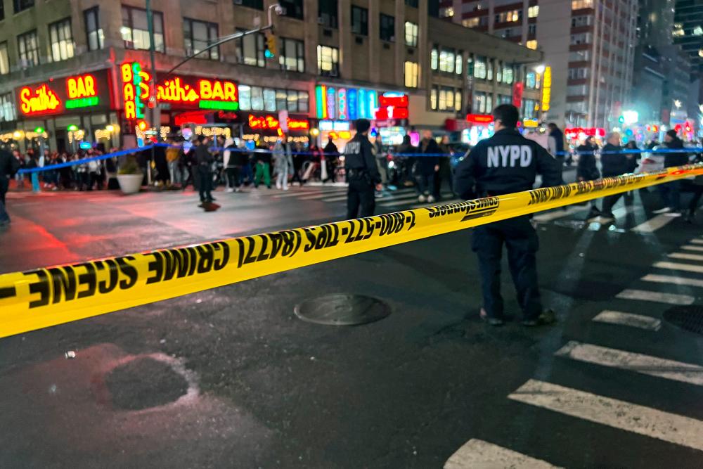 Police officers stand behind a cordon after a fatal shooting in New York City on February 9, 2023. A 22-year-old man was shot and killed near a Shake Shack in Midtown Manhattan during the evening rush hour on February 9, 2023, and police were searching for two gunmen hours later. AFPPIX