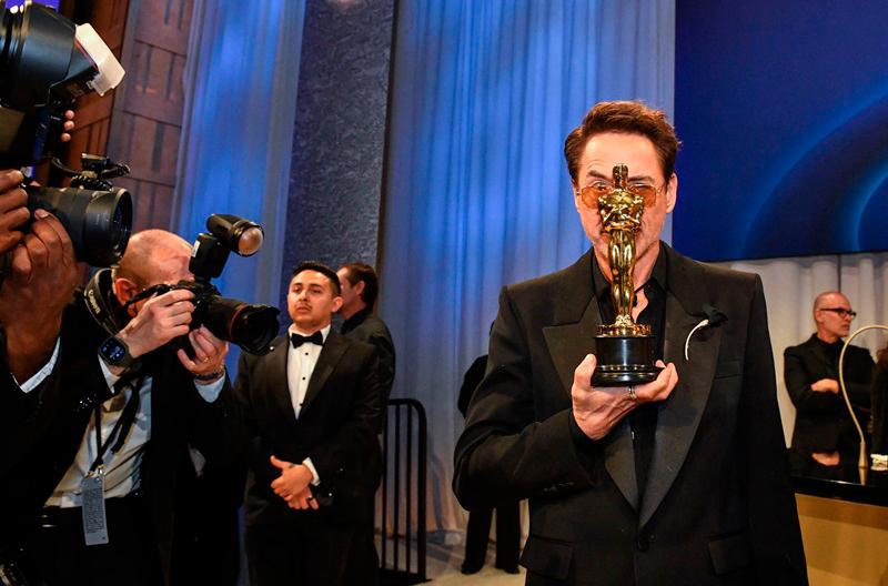 $!Photographers take pictures of US actor Robert Downey Jr. as he holds the Oscar for Best Actor in a Supporting Role//AFP