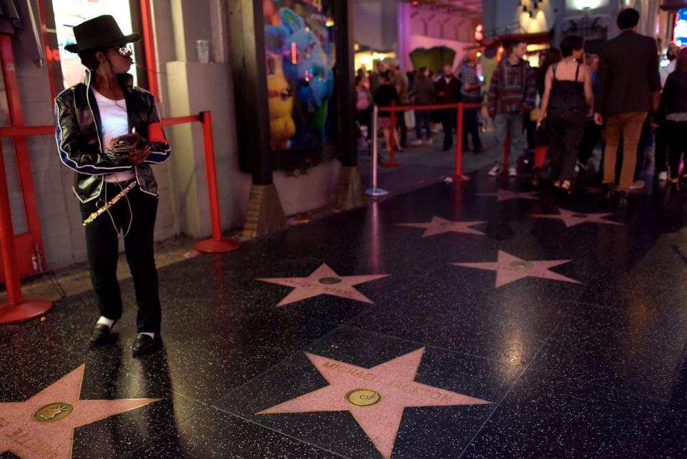 A woman dressed as Michael Jackson stands next to his Hollywood Walk of Fame star in Hollywood on June 23, 2019. Defiant fans are preparing to mark 10 years since Michael Jackson’s death as fascination with the King of Pop remains undimmed despite lurid claims of child sex abuse. On Hollywood’s Walk of Fame, the singer’s star continues to draw a constant scrum of selfie-snapping tourists, while nearby souvenir shops, street performers and even tattoo parlors report a brisk trade in all things Jackson. MJ/ AFP / Agustin PAULLIER