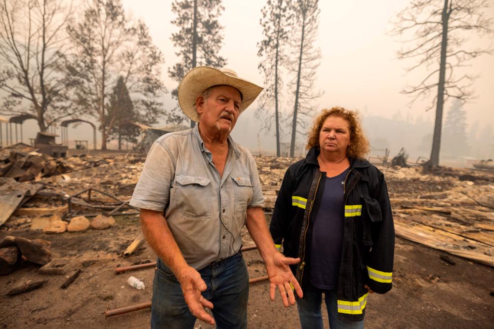 Rancher Gary Rainey and volunteer fire department chief Janet Jones talk to a reporter at the ruins of the century old Klamath River Community Hall, which was destroyed by the McKinney Fire, in the Klamath National Forest northwest of Yreka, California, on August 1, 2022. AFPPIX