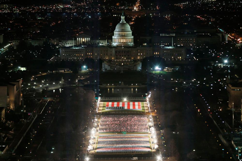 The “Field of Flags” is illuminated on the National Mall as the U.S Capitol Building is prepared for the inauguration ceremonies for President-elect Joe Biden on January 18, 2021 in Washington, DC. Approximately 191,500 U.S. flags will cover part of the National Mall and will represent the American people who are unable to travel to Washington, DC for the inauguration. Joe Raedle/Getty Images/AFP