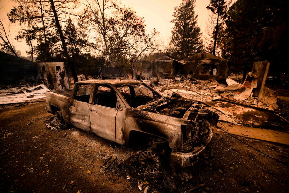 The carcass of a burned car is seen next next to a house reduced to ashes by the Glass Fire in Napa Valley, California on September 28, 2020. — AFP