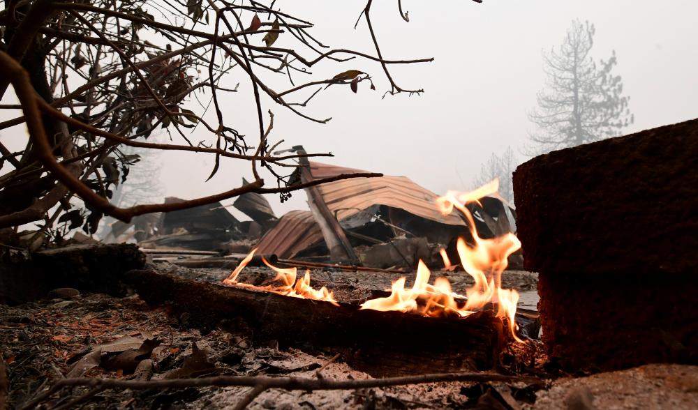 Charred trees and burning embers remain amid fire-ravaged homes during the Creek fire in Auberry, Fresno County on September 11, 2020. — AFP