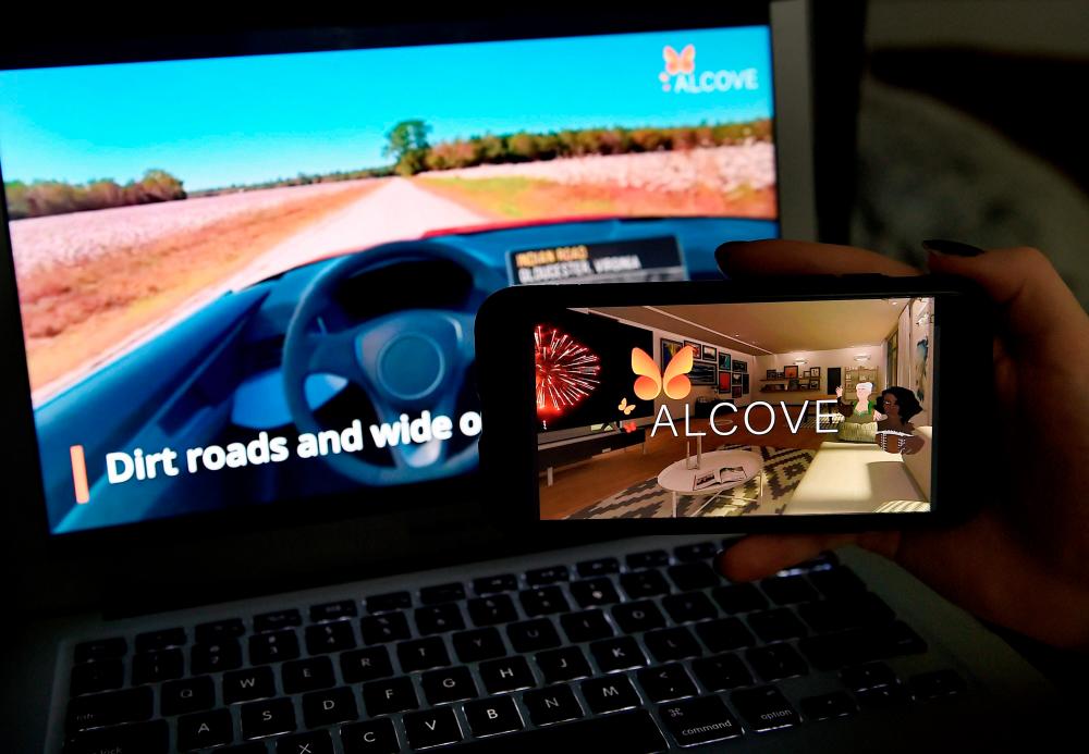 This illustration picture shows a virtual road trip on a computer and the travel application logo from Alcove displayed on a smartphone in Arlington, Virginia on March 19, 2021. - AFP