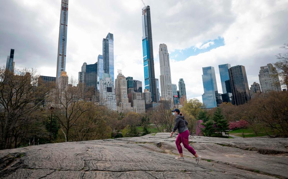 A woman wearing a mask walks in the almost deserted Central Park in Manhattan on April 16, 2020 in New York City. — AFP