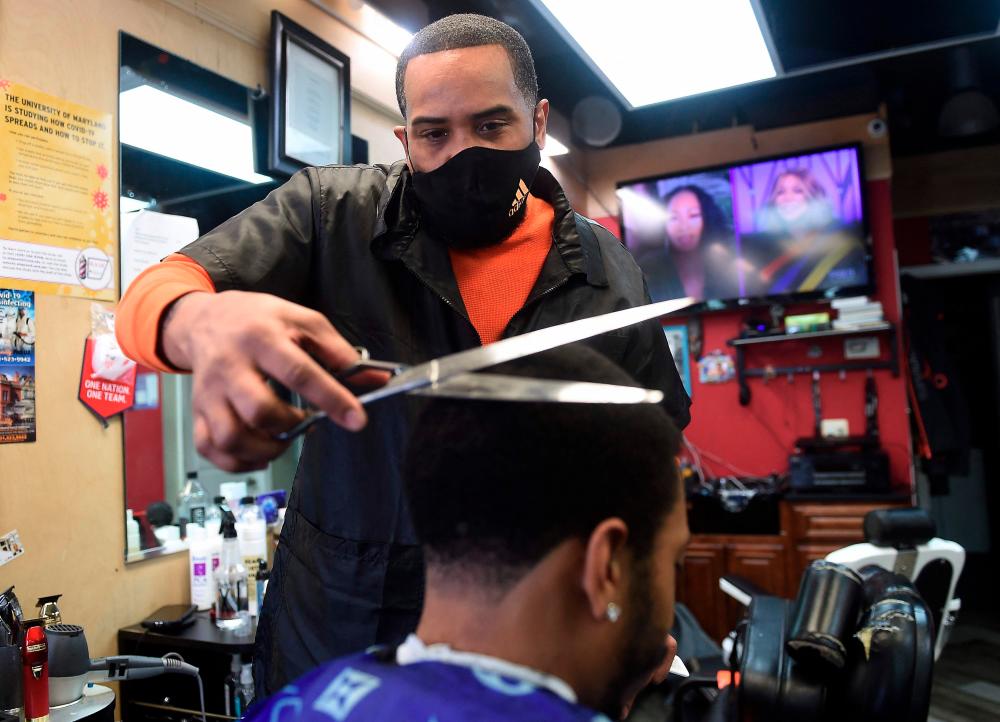Mike Brown cuts the hair of Kendrick Furbush at The Shop Hair Spa in Hyattsville, Maryland on February 25, 2021. - AFP