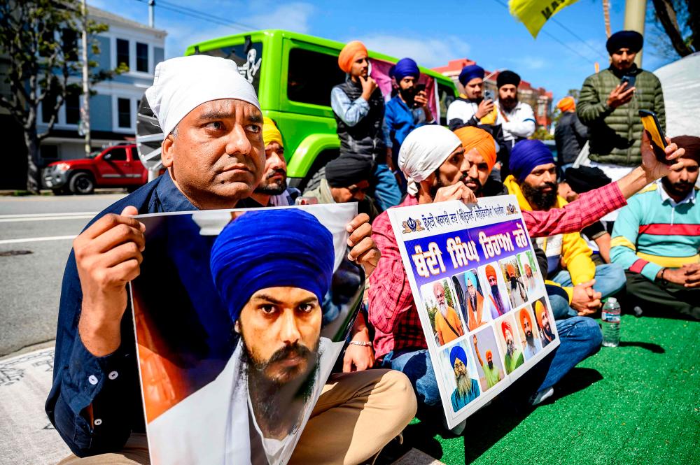 Raman Singh (L) holds a photo of Sikh organizer Amritpal Singh while protesting against the Indian government outside the Indian Consulate in San Francisco on March 20, 2023/AFPPix