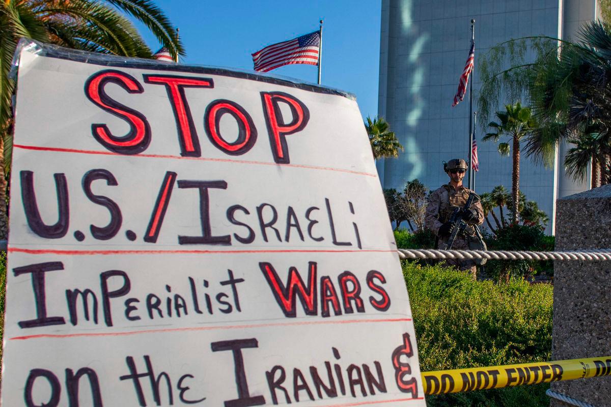 US Marines watch as protesters hold signs during a “No War on Iran” demonstration outside the Wilshire Federal Building in Los Angeles - AFPPIX
