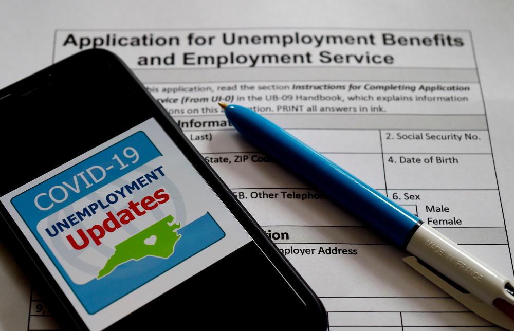 nemployment Assistance Updates logo is displayed on a smartphone on top of an application for unemployment benefits. – AFPPIX