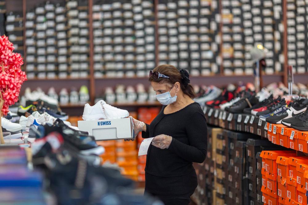 An employee stocks merchandise at a Shoe City store as Los Angeles County retail businesses reopen while the Covid-19 pandemic continues on May 27, 2020 in Glendale, Californias latest guidelines and allow the resumption of in-store shopping at low-risk retail stores, faith-based services, drive-in theaters and other recreational activities with reduced capacities and social distancing restrictions. — AFP