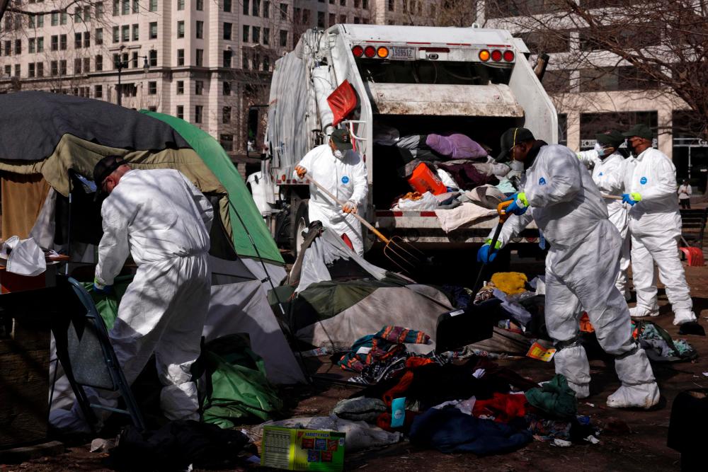 WASHINGTON, DC - FEBRUARY 15: Members of a clean-up crew remove belongings that have been left behind by occupants as the National Park Service clears the homeless encampment at McPherson Square on February 15, 2023 in Washington, DC. AFPPIX