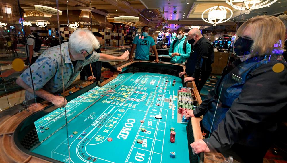 Guests play craps on a table with plexiglass safety shields at Bellagio Resort &amp; Casino on the Las Vegas Strip after the property opened for the first time since being closed on March 17 because of the coronavirus (Covid-19) pandemic on June 4, 2020 in Las Vegas, Nevada. — AFP