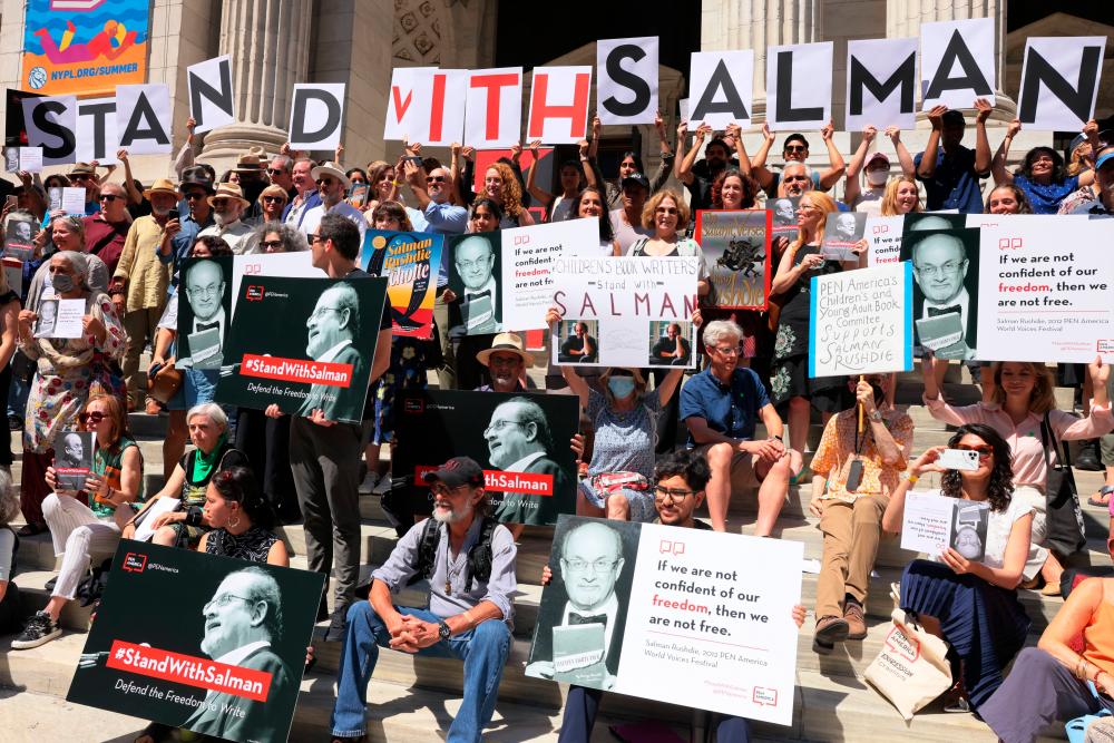 NEW YORK, NEW YORK - AUGUST 19: People hold signs as they gather at the steps of the New York Public Library to show support for Salman Rushdie on August 19, 2022 in New York City. AFPPIX