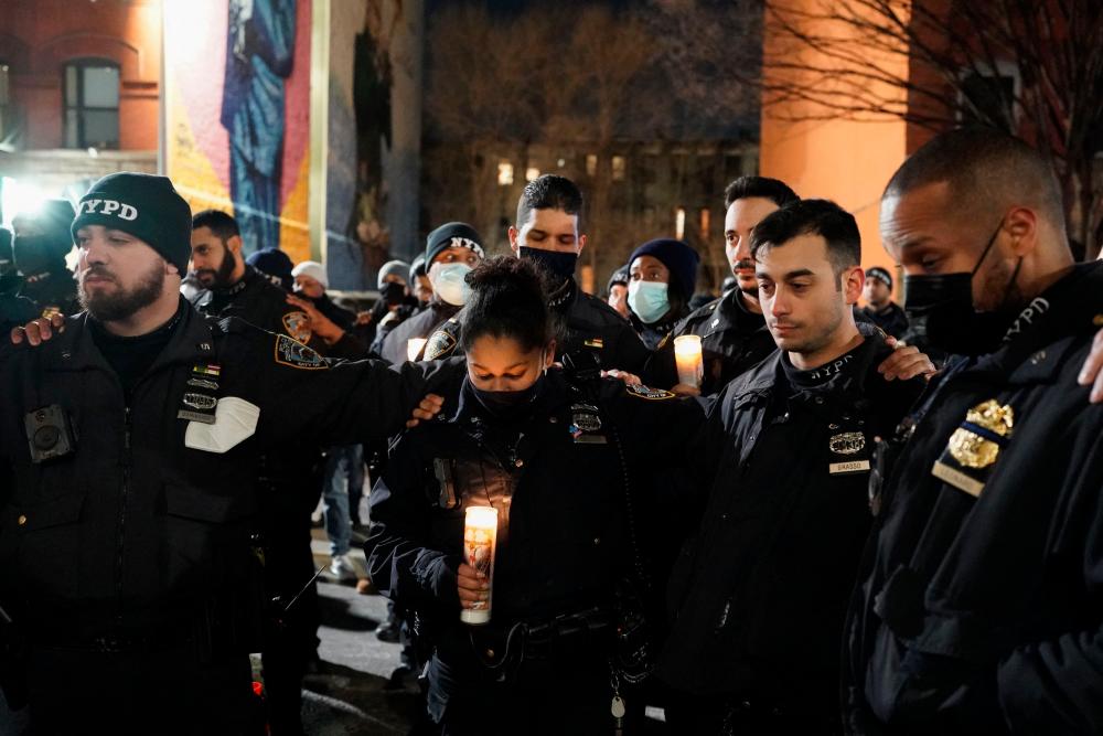Police officers hold candles as they attend a vigil following the shooting of two police officers in Harlem, New York on January 22, 2022. AFPPIX