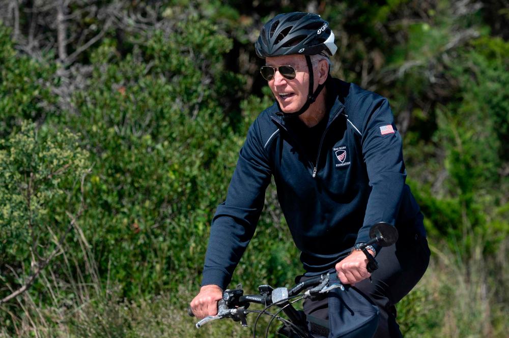 US President Joe Biden rides his bike through Cape Henlopen State Park in Rehoboth Beach, Delaware, on September 19, 2021. US President Joe Biden has requested early talks with French President Emmanuel Macron, France said on Sunday, in an apparent effort to mend fences after a row over a submarines contract sparked rare tensions between the allies/AFPPix