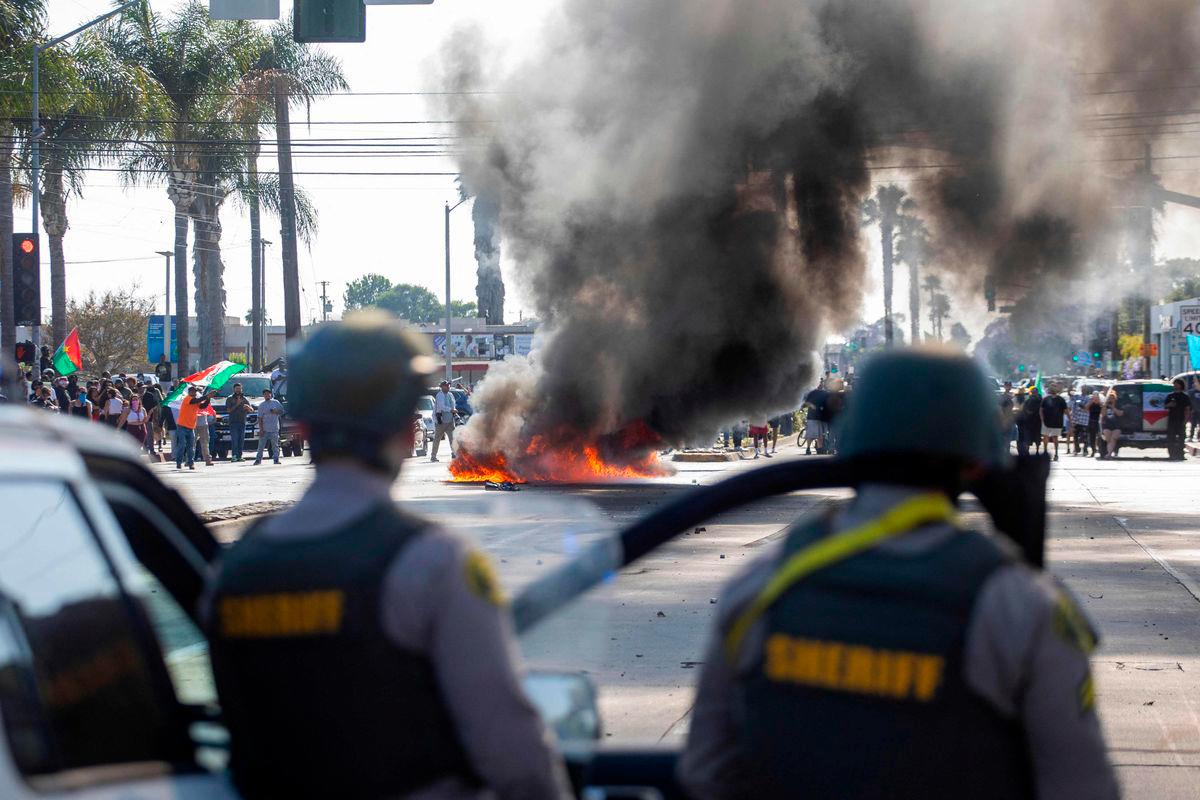 A car burns as law enforcement clashes with demonstrators during a protest following federal immigration operations, in the Compton neighborhood of Los Angeles, California on June 7, 2025. AFP