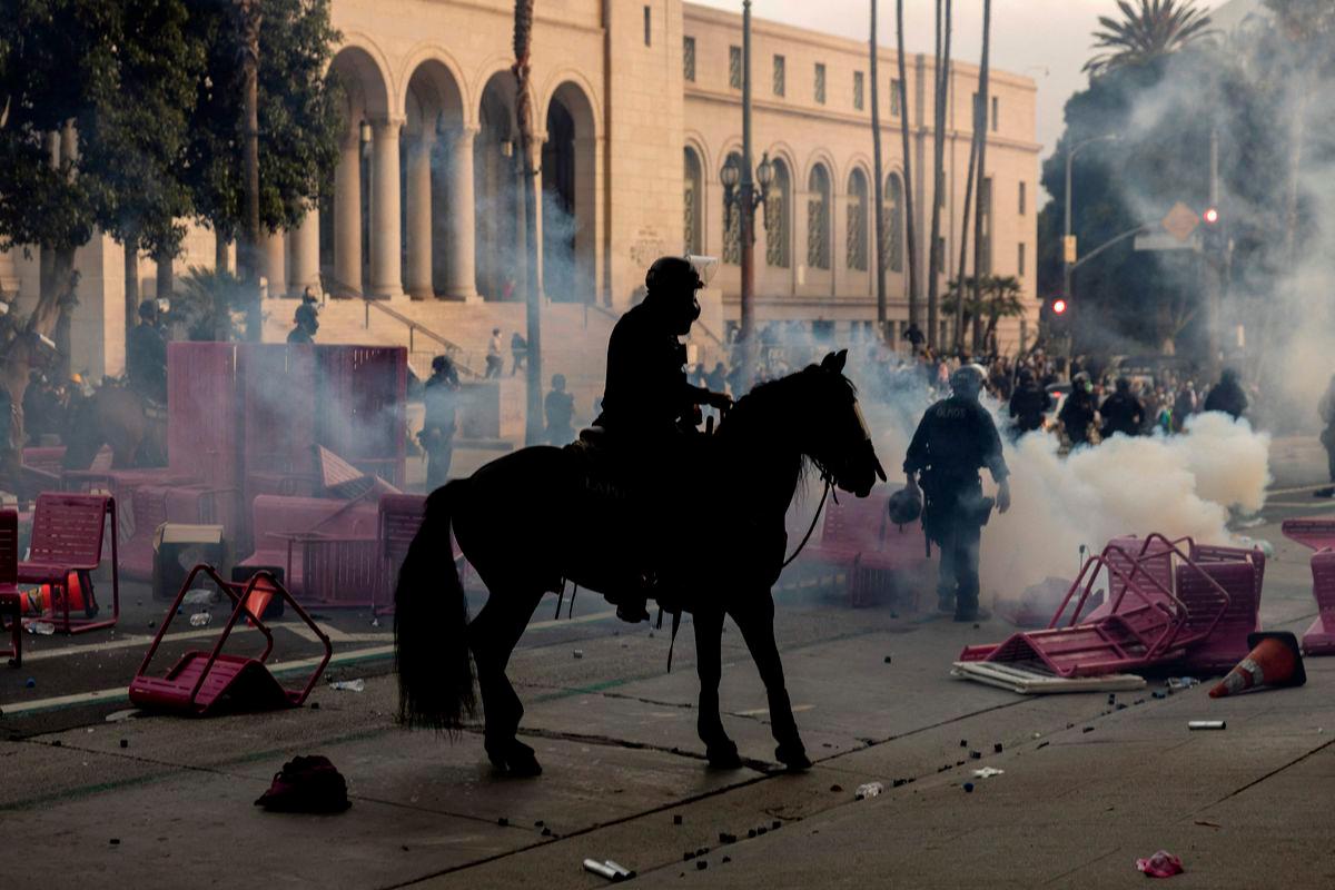 Los Angeles mounted police advance on a makeshift barricade in a cloud of tear gas as clashes erupt with demonstrators next to City Hall during a protest following federal immigration operations, in Los Angeles, California on June 8, 2025.